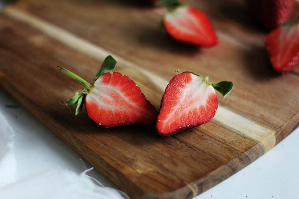 cut strawberries on wooden cutting board