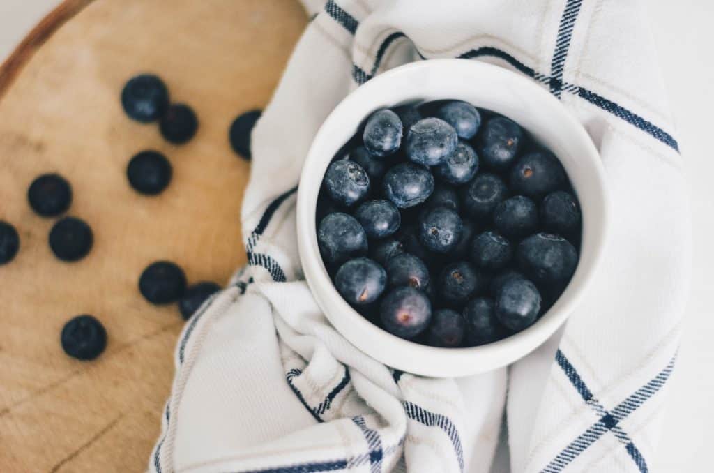 bowl of blueberries on white cloth