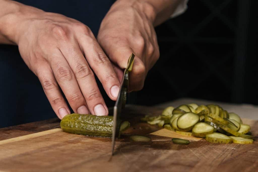 knife cutting pickled cucumbers